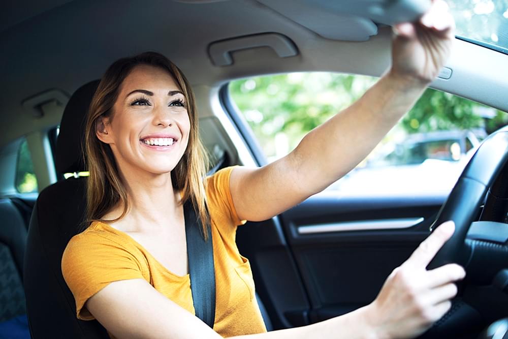 Car interior view of female woman driver adjusting mirrors before driving a car.