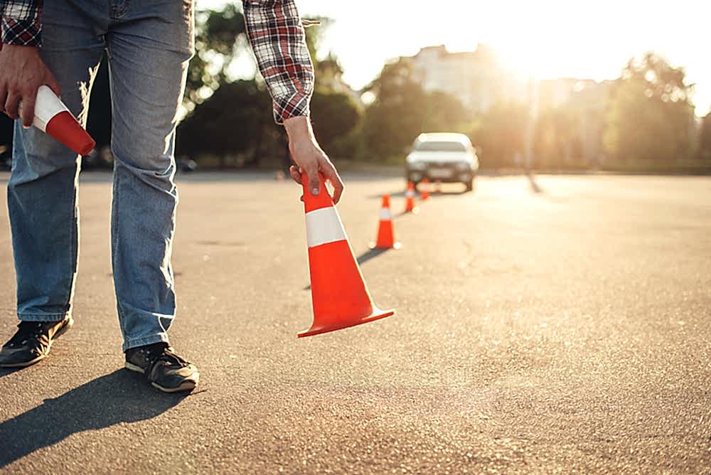 Instructor sets the cone for the examination, driving school concept. lesson for novice car drivers, test for beginner